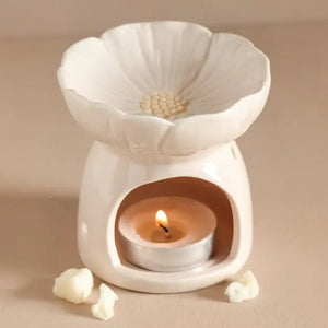 Elegant white ceramic flower wax melt warmer with lit tealight candle, featuring daisy-inspired design, scalloped petals, and minimalist modern home decor aesthetic